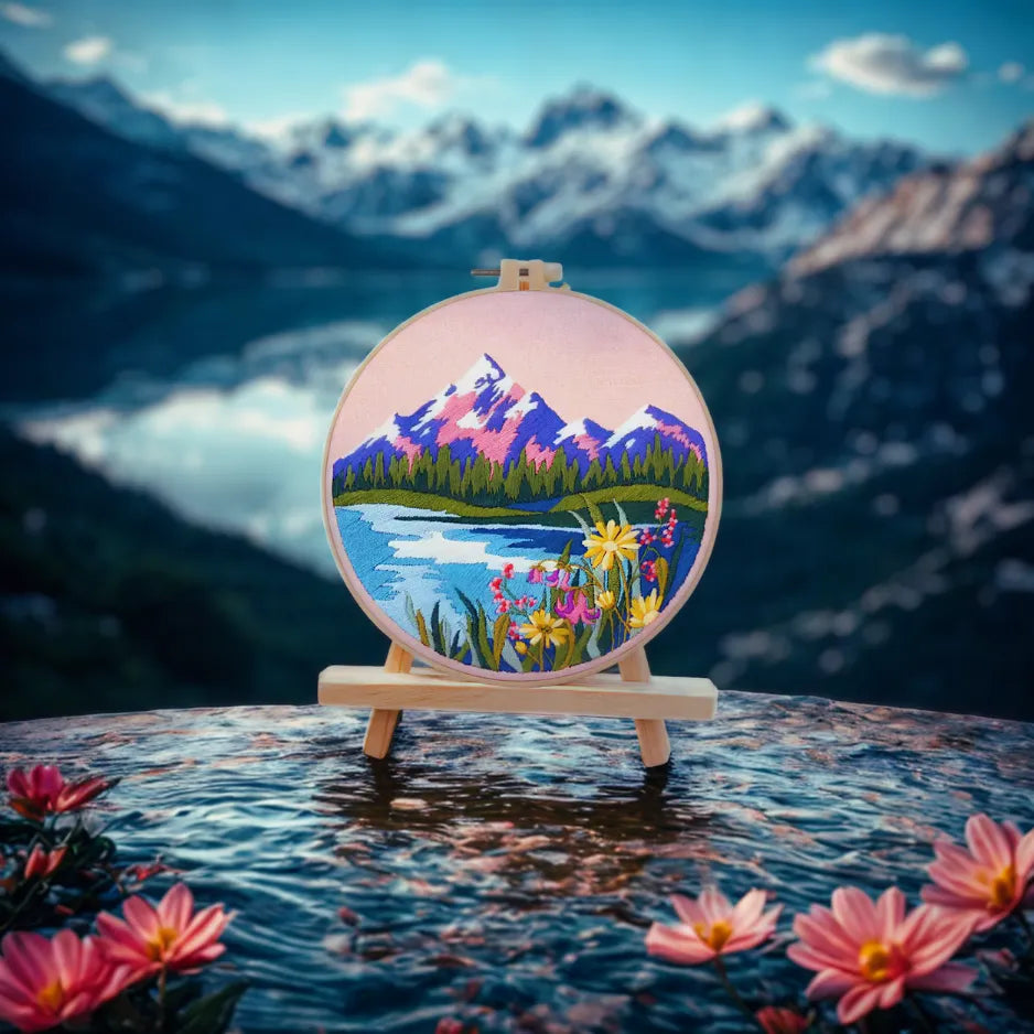 Embroidery hoop with mountain and floral design in front of a mountain landscape