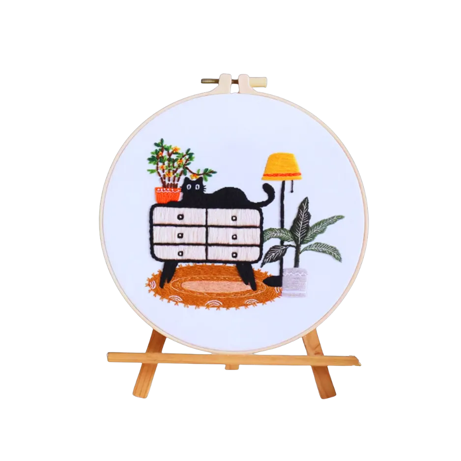 Embroidery hoop with a cat and furniture design on a white background