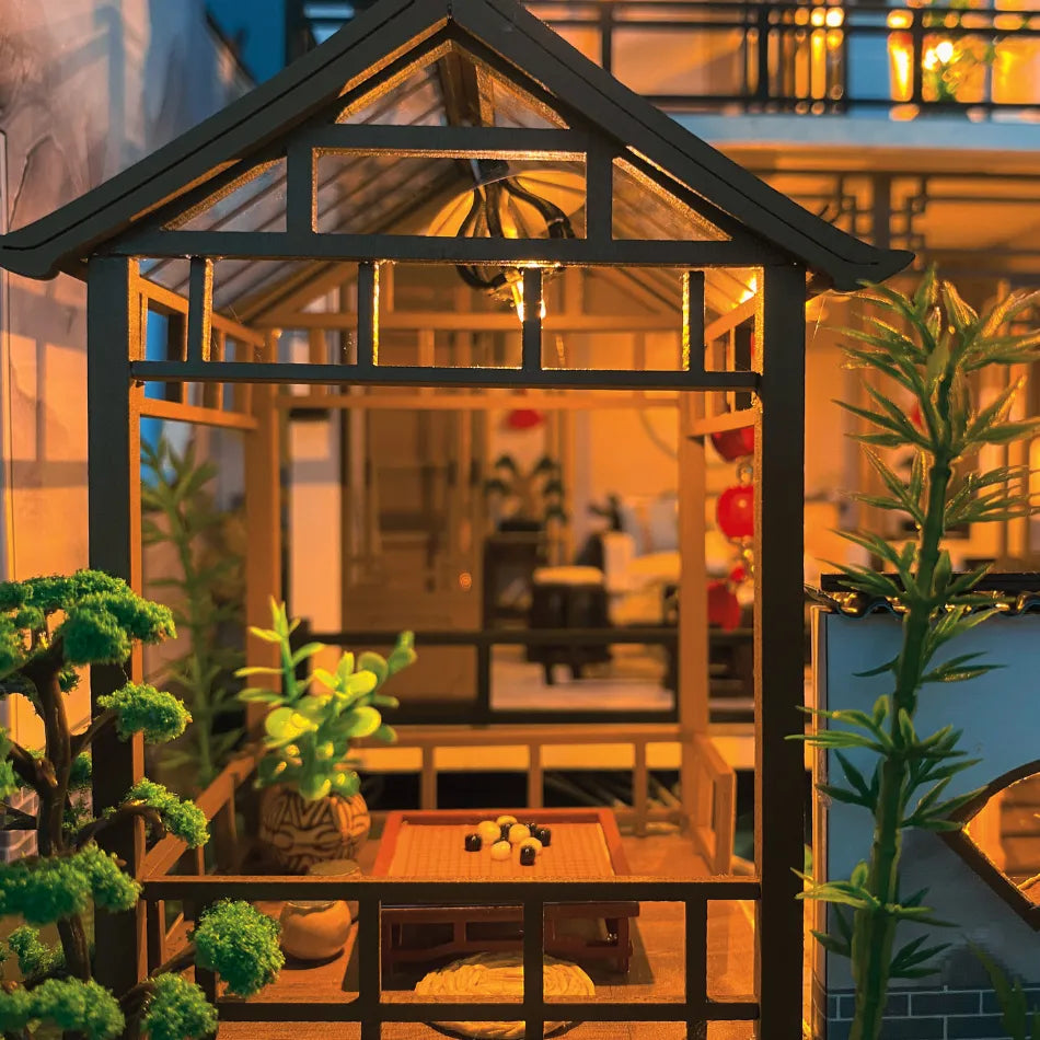 Small glasshouse with plants inside, illuminated by warm light, on a balcony.