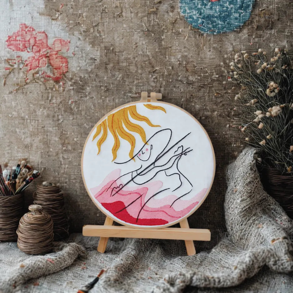 Embroidery hoop with a woman's face design on a textured fabric background