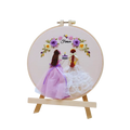 Embroidery hoop with two brides and flowers on a white background