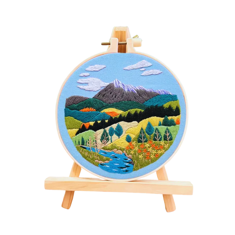 Embroidery hoop with a mountain landscape design on a white background