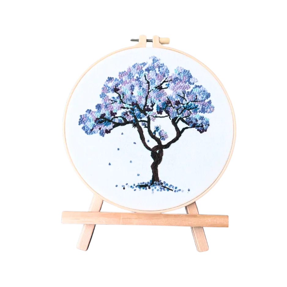 Embroidery hoop with a blue floral tree design on a white background