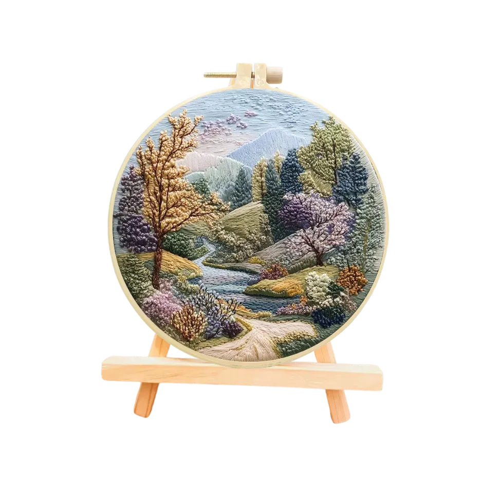 Embroidered landscape hoop art on a stand with a scenic design of trees and mountains.