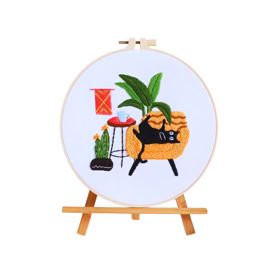 Embroidery hoop with a cat lounging in a basket design on a white background