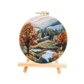 Embroidery hoop with a landscape design featuring trees and water on a white background