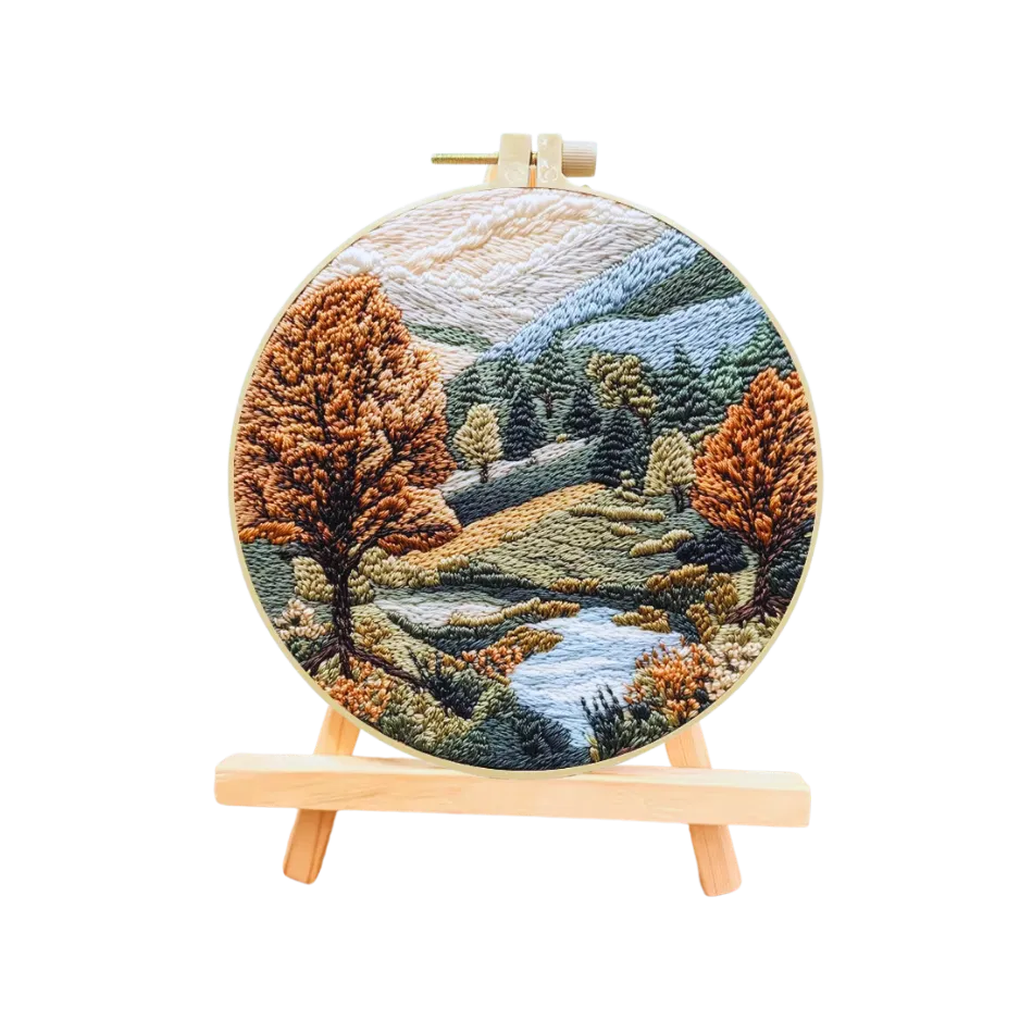 Embroidery hoop with a landscape design featuring trees and water on a white background