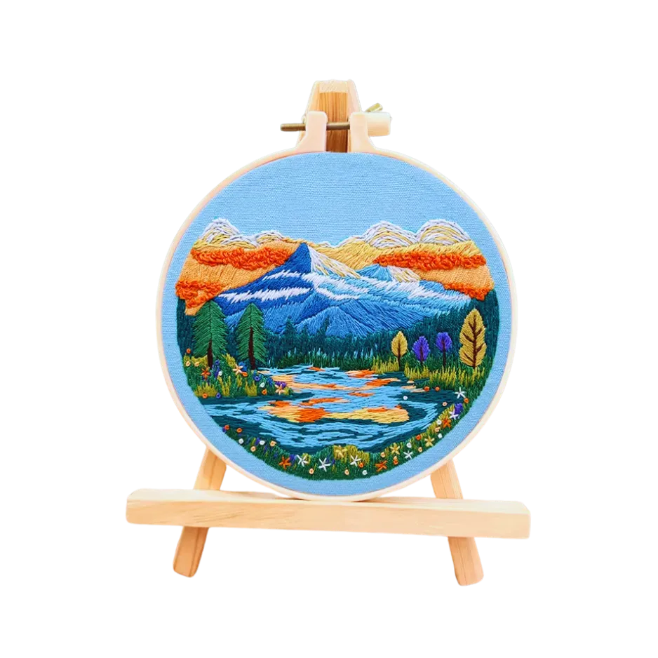 Embroidery hoop with a mountain landscape design on a white background