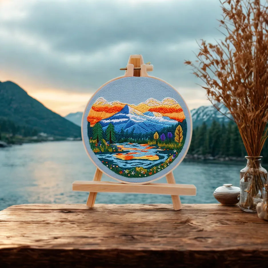 Embroidery of a mountain landscape on an easel with a scenic background