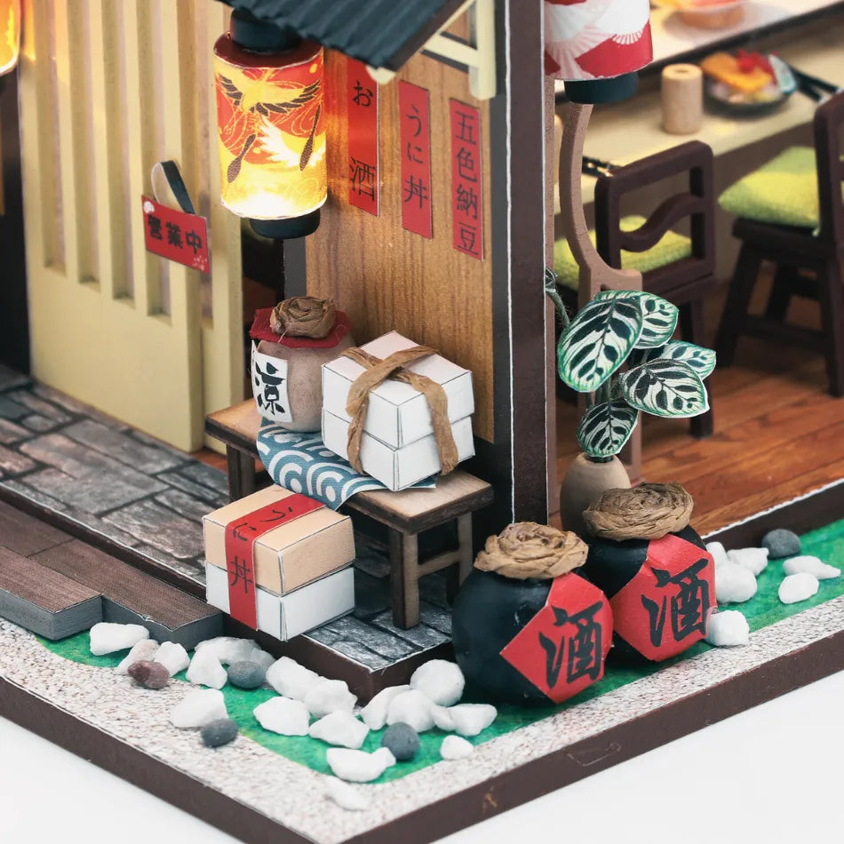 Miniature model of a Japanese restaurant with lantern, boxes, and plants.
