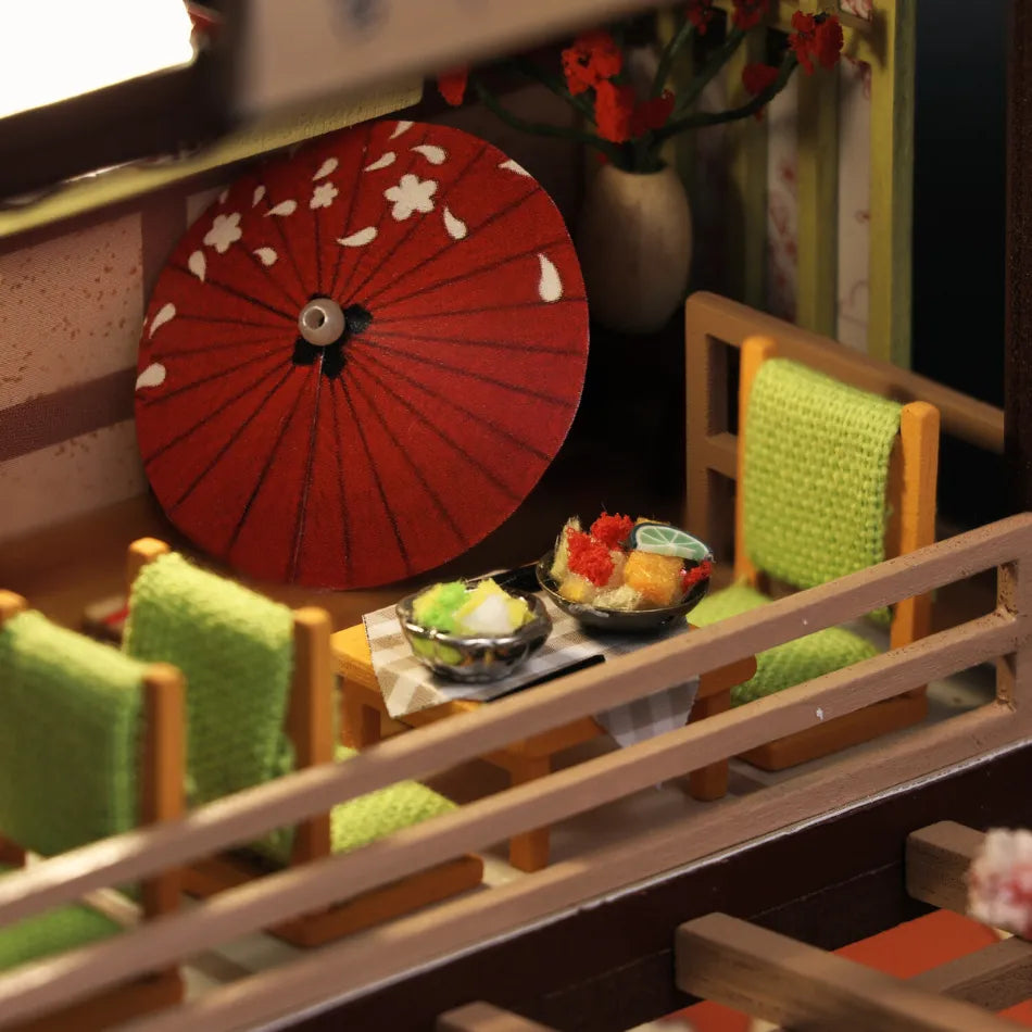 Miniature model of a Japanese restaurant with red umbrella and green chairs.