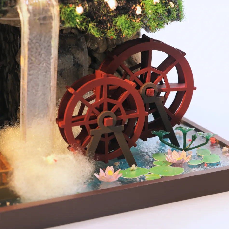 Decorative water fountain with red gears and water lilies on a white surface