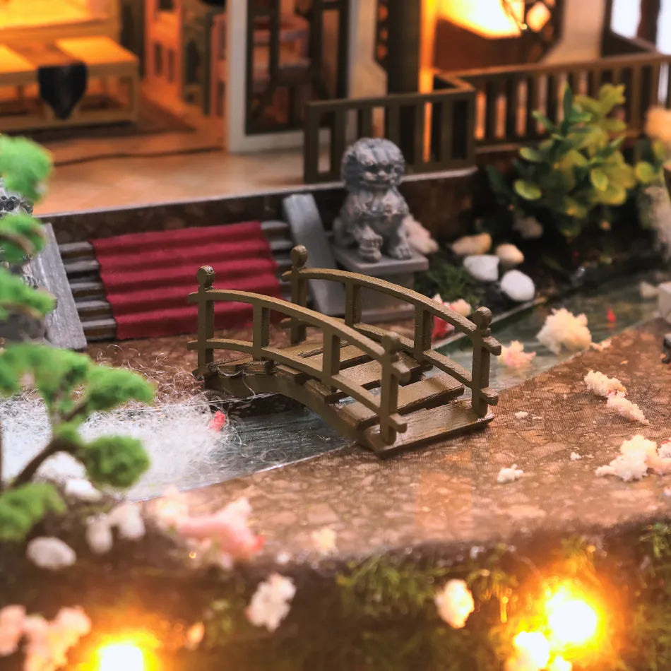 Miniature garden scene with a bridge, pond, and decorative elements.