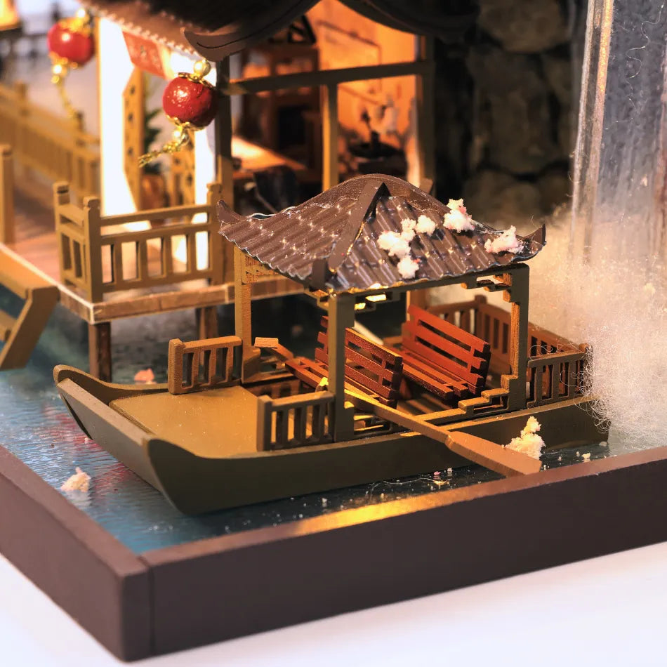 Model of a traditional Chinese house with a thatched roof on a small platform.