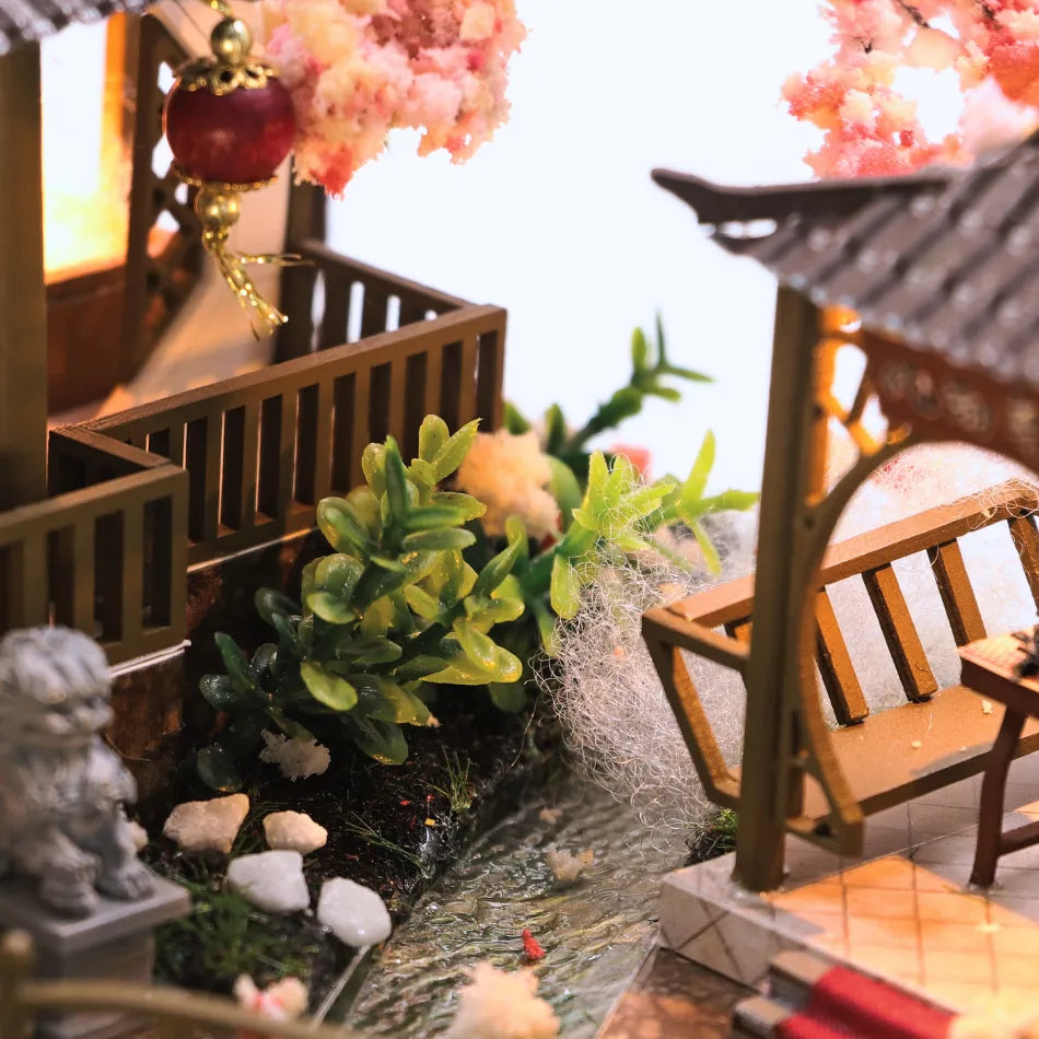 Miniature garden scene with a wooden bridge, plants, and a small pagoda.