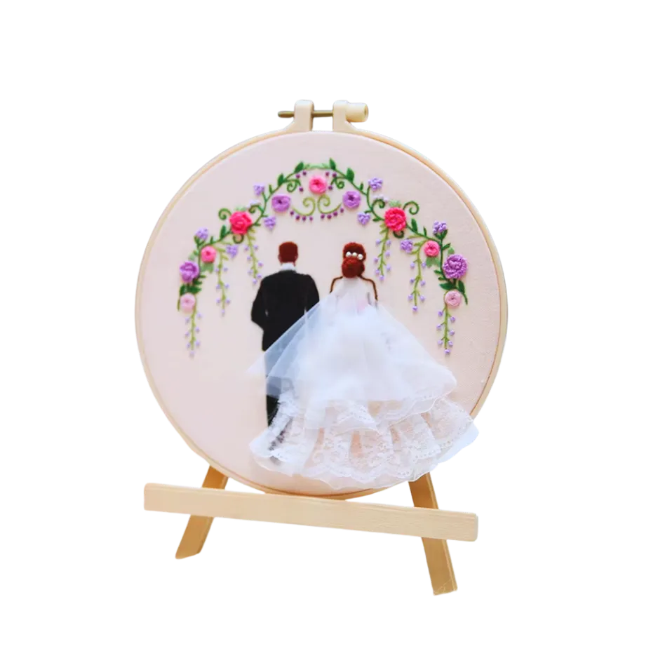 Embroidery hoop with a couple under a floral arch on a white background