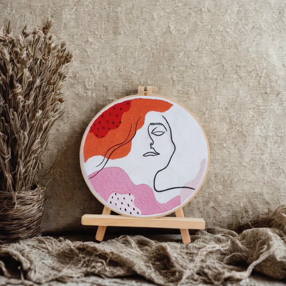 Embroidery hoop with abstract design of a face on a textured surface