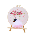 Embroidery hoop with cherry blossom design and a couple under a tree on a white background