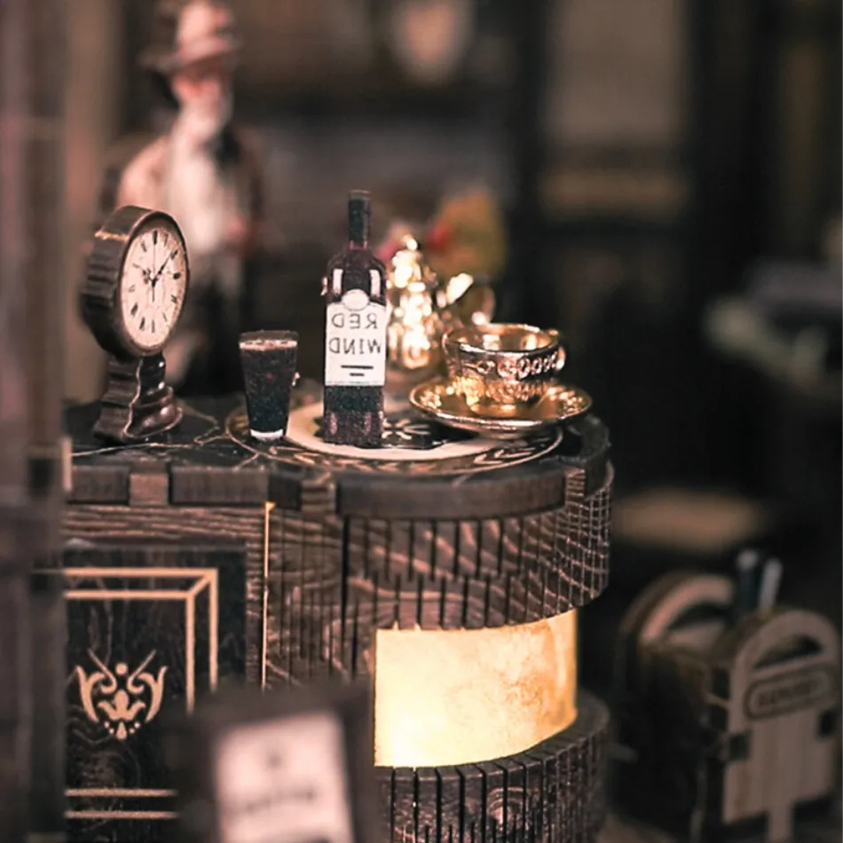 Decorative table setting with a bottle, glasses, and clock on a dark surface.