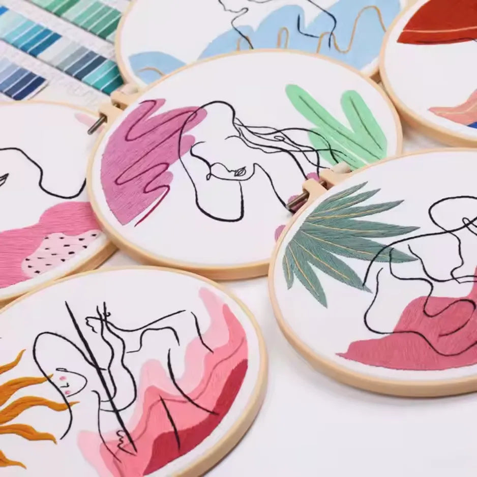 Set of embroidery hoops with abstract line art and colorful backgrounds on a white surface