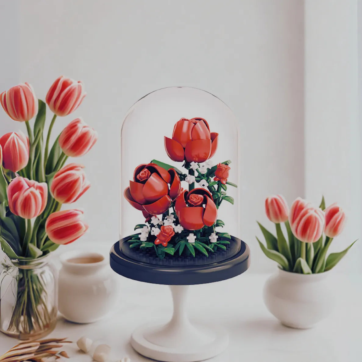 Decorative display of red roses under a glass dome on a white surface.